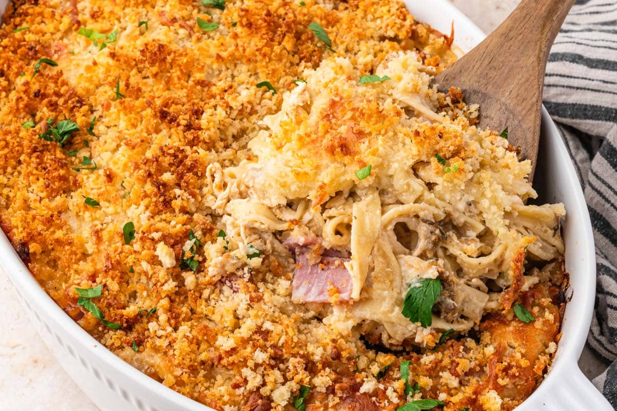 a wooden spoon puling out creamy chicken cordon bleu bake