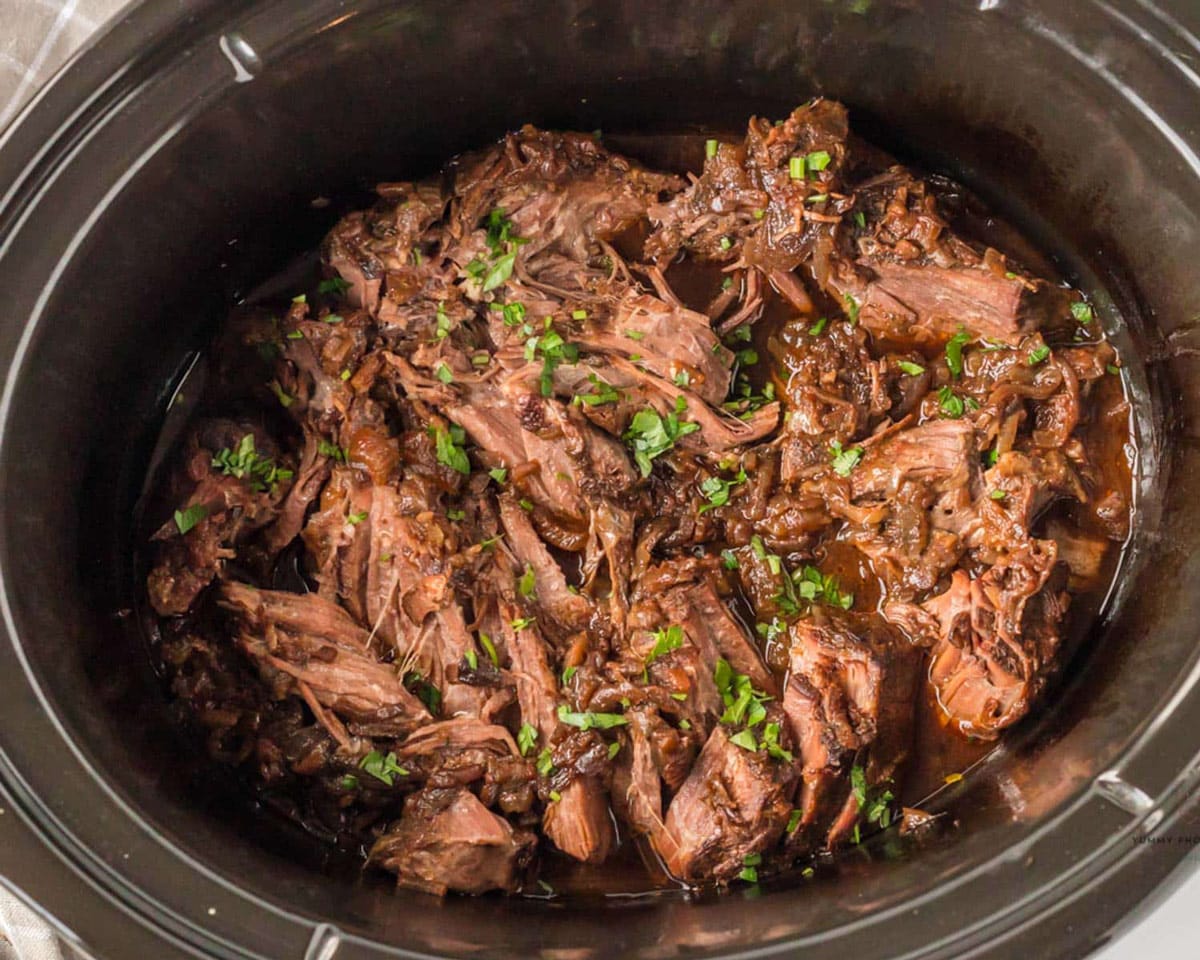 french onion pot roast cooked in a slow cooker with fresh parsley on top