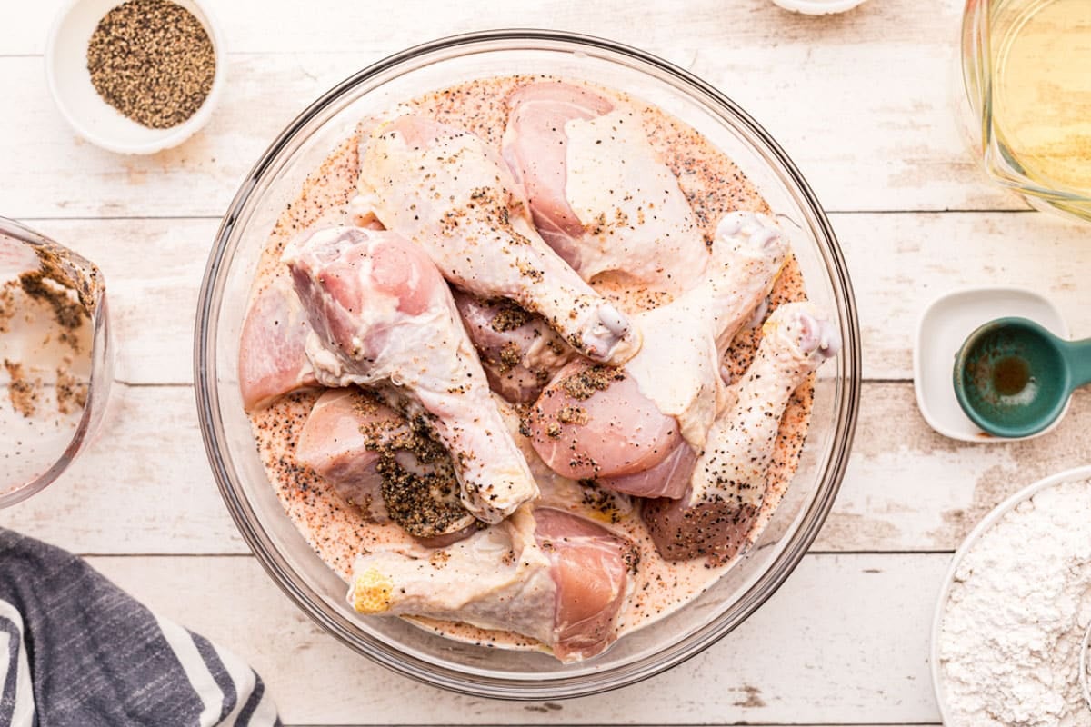 chicken legs soaking in buttermilk in a bowl