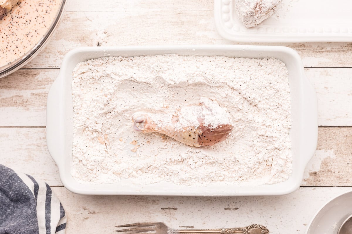 a chicken leg in flour in a dish