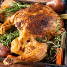 a whole roasted chicken on a table with veggies