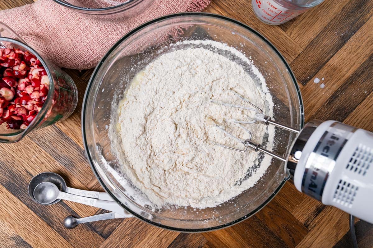 adding flour to cake batter in a glass bowl