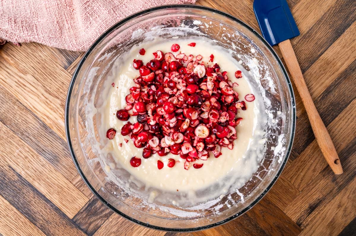 chopped cranberries on top of cake batter in a bowl
