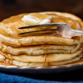 a stack of 4 homemade pancakes with a fork cutting into them