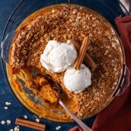 overhead view of pumpkin crisp with ice cream and cinnamon sticks