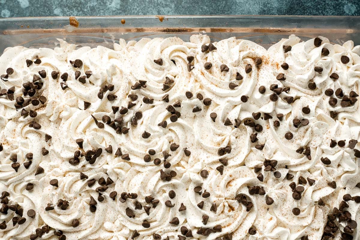 swirls of white frosting and chocolate chips in a baking pan