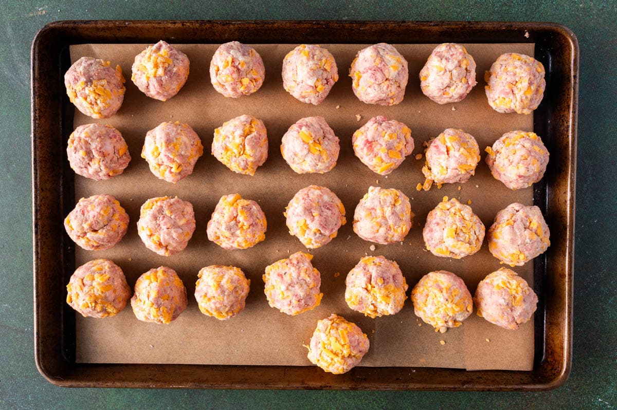 unbaked sausage meatballs on a baking pan