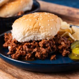 homemade sloppy joes on a plate with pickles and chips