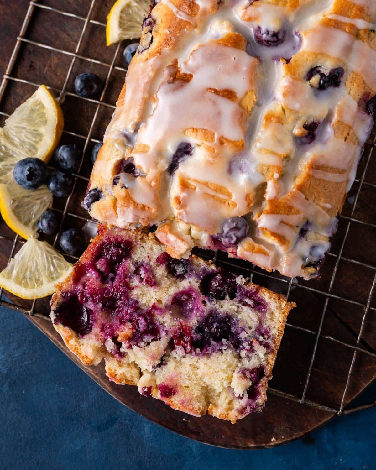 overhead view of a loaf of blueberry lemon bread on a table with one slice cut