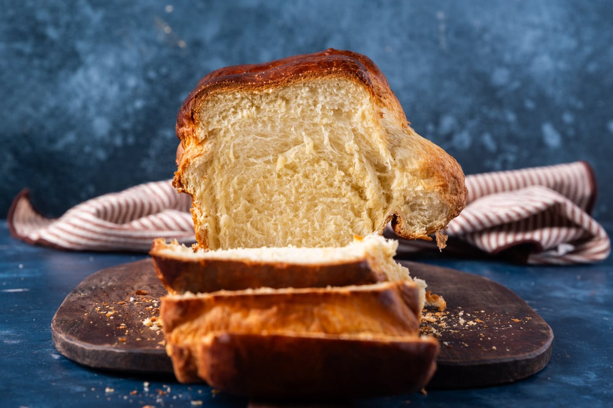 milk bread loaf sitting on a table with one slice cut