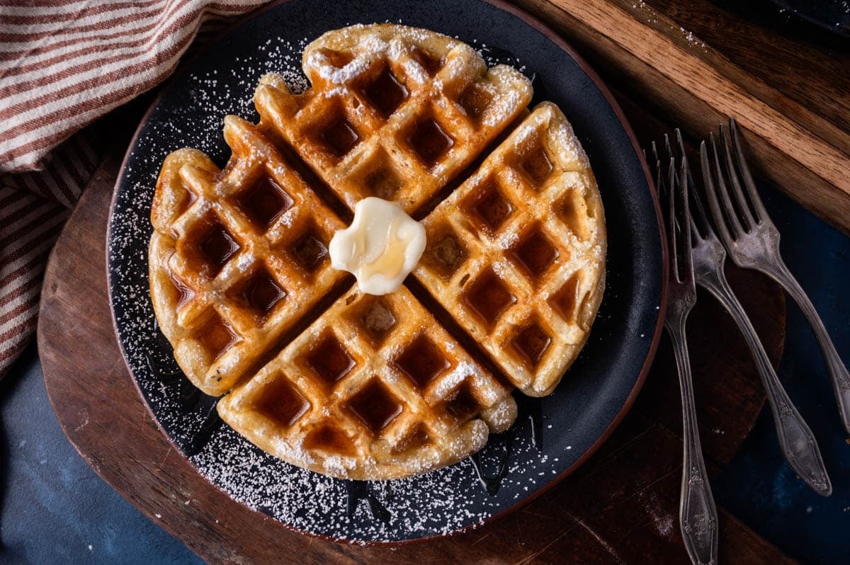 a plate with a sourdough waffle on it with butter and syrup