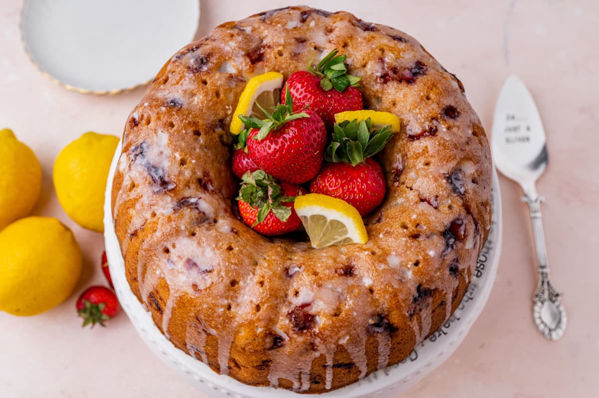 strawberry lemonade cake on a table with plates and a spatula