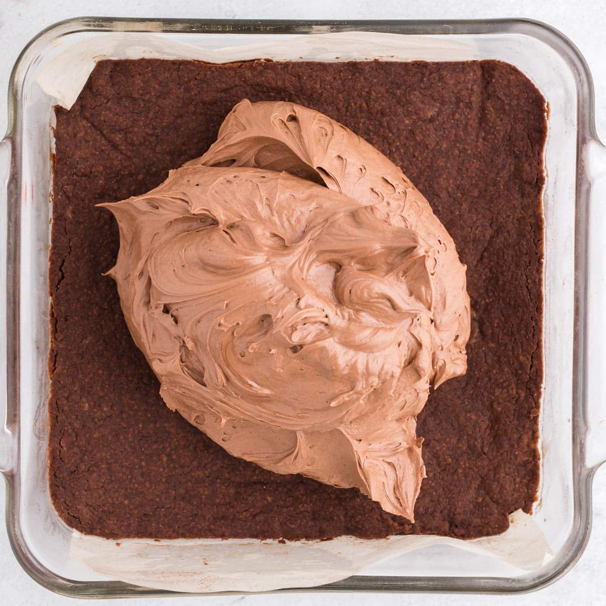 chocolate frosting dolloped over chocolate brownies