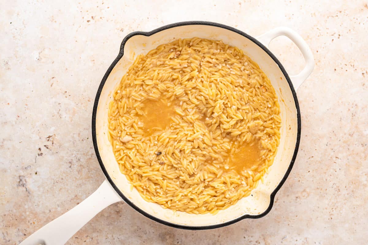 orzo and chicken stock in a skillet