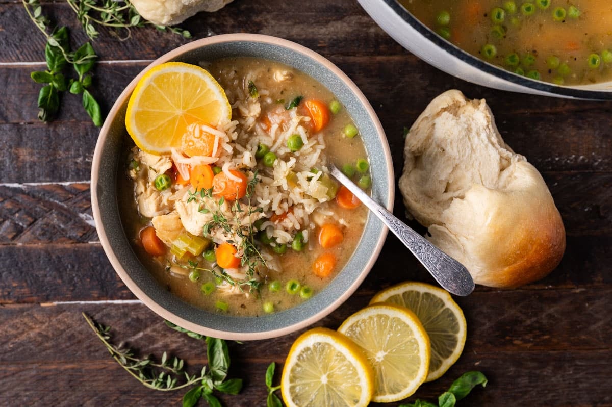 a bowl of chicken soup with lemon and rice on a table