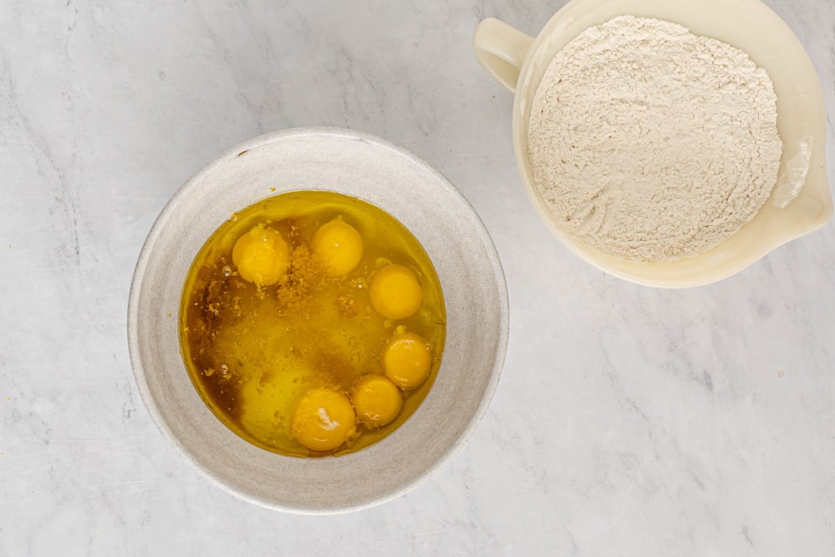 eggs, sugar and vanilla in a bowl and flour in another bowl on a table