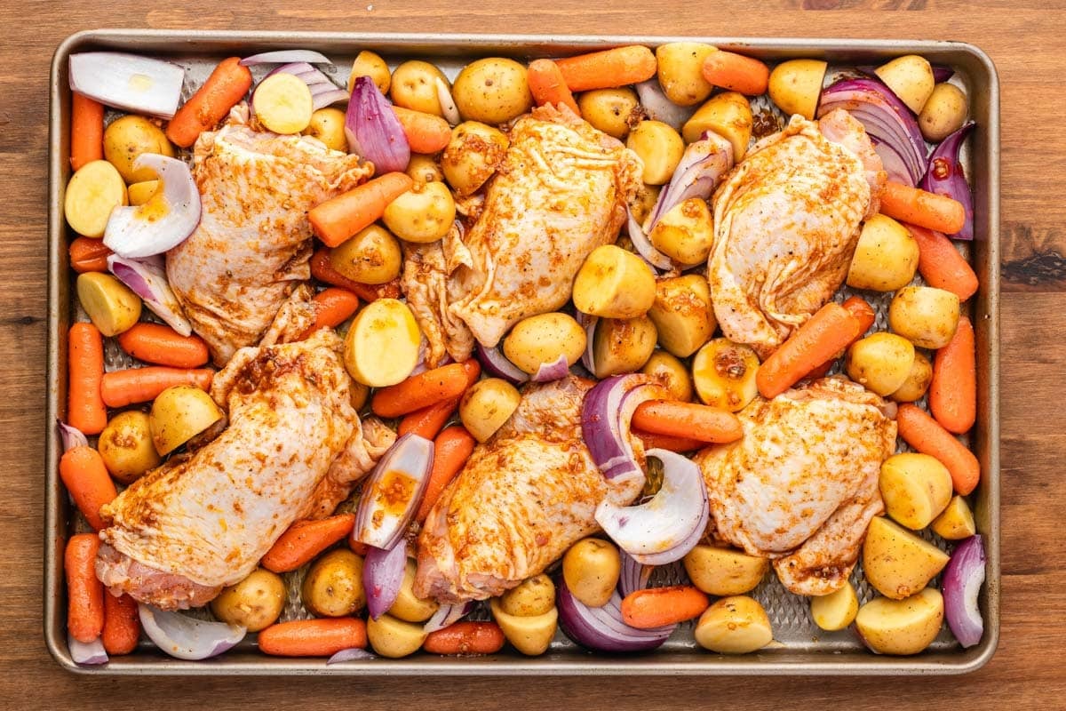 uncooked chicken and veggies on a sheet pan