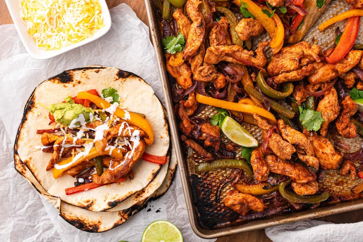 sheet pan chicken fajitas on a table with tortillas