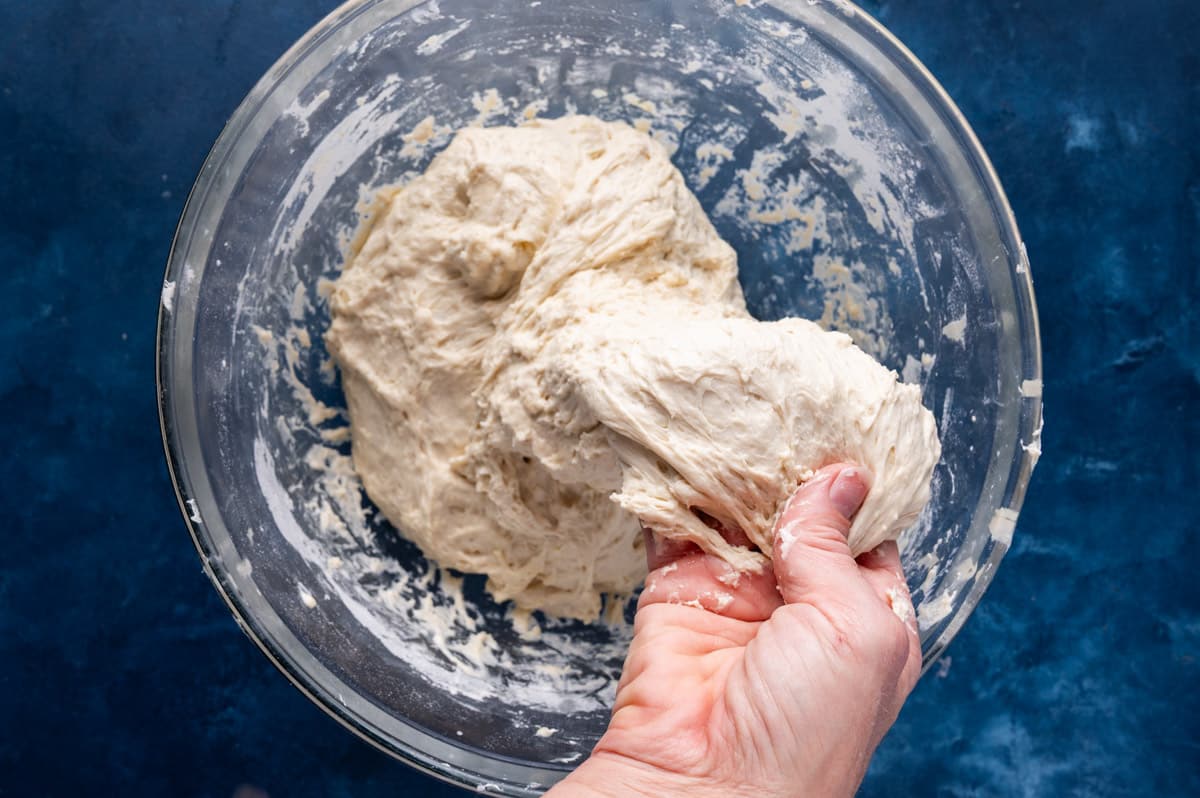 a hand pulling dough to fold it