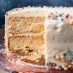 a two layer white cake with white frosting, with a slice cut out