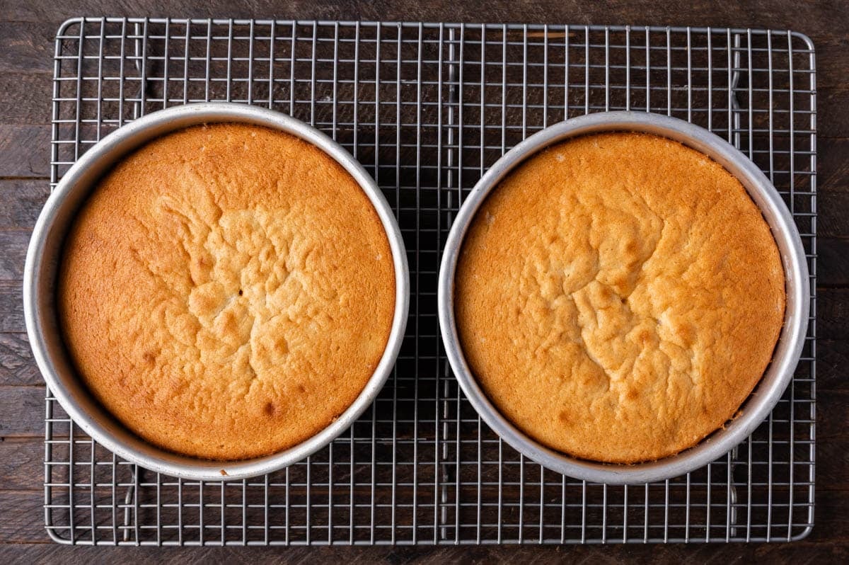 two baked white cakes on a wire rack