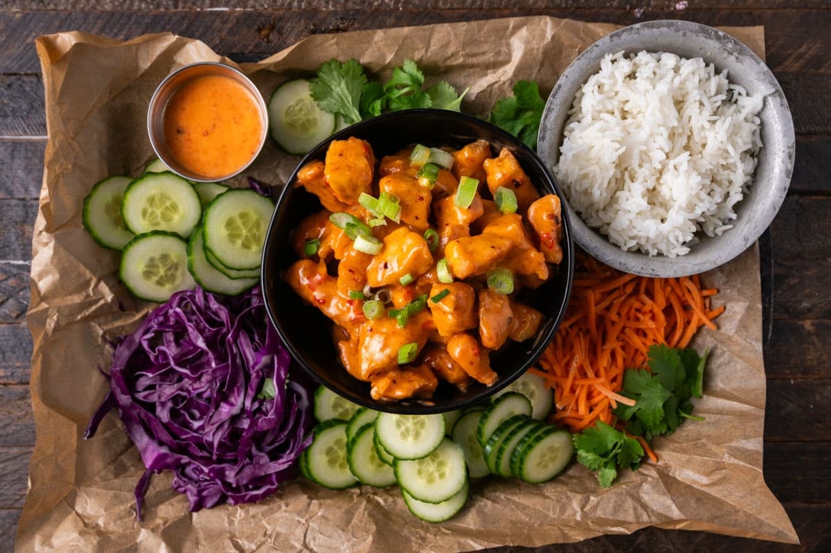 ingredients for a chicken bowl with bang bang sauce on a table