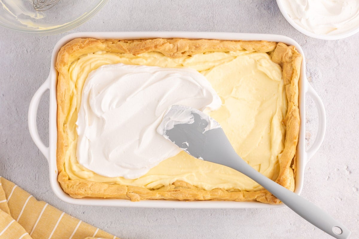 spreading whipped cream over pudding in a dessert