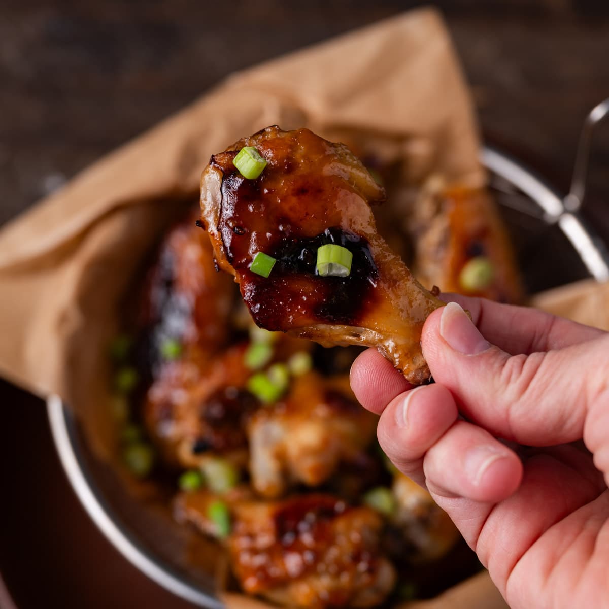 a hand holding a wing with honey sauce