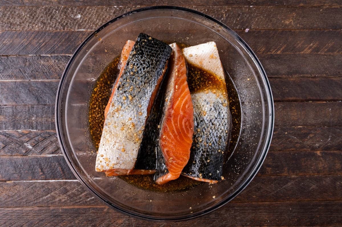 salmon marinating in a glass bowl