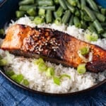 a piece of honey garlic salmon on a bed of rice with green beans
