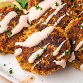 a pile of salmon patties with mayo sauce on a plate