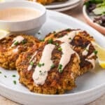 3 salmon patties on a plate with spicy mayo sauce