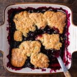 overhead view of blueberry cobbler with golden biscuit top in a pan