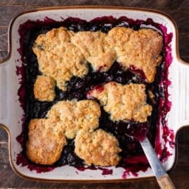 overhead view of blueberry cobbler with golden biscuit top in a pan