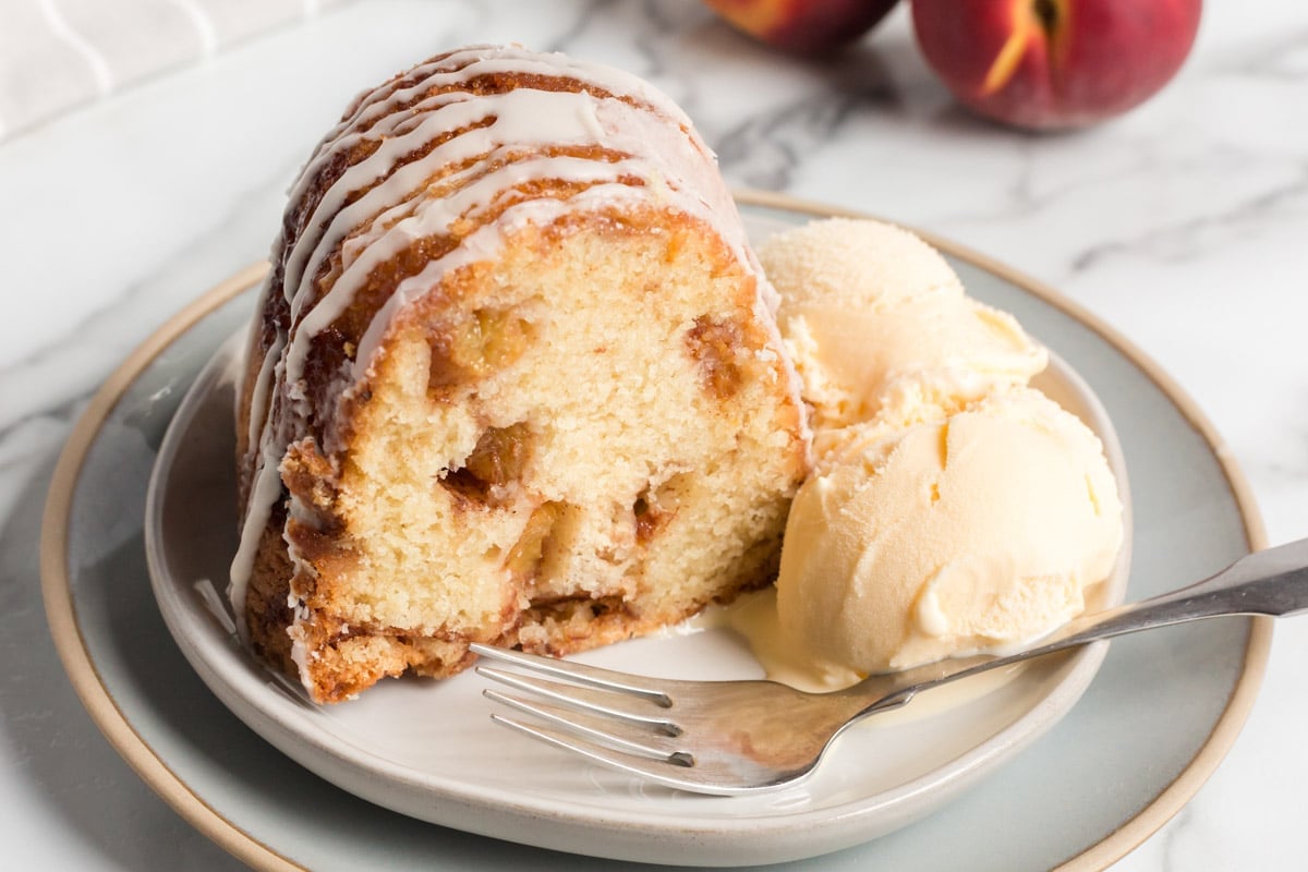 a slice of a slice of cinnamon peach bundt cake on a plate with ice cream