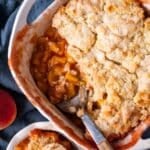 peach cobbler in a pan with one serving out