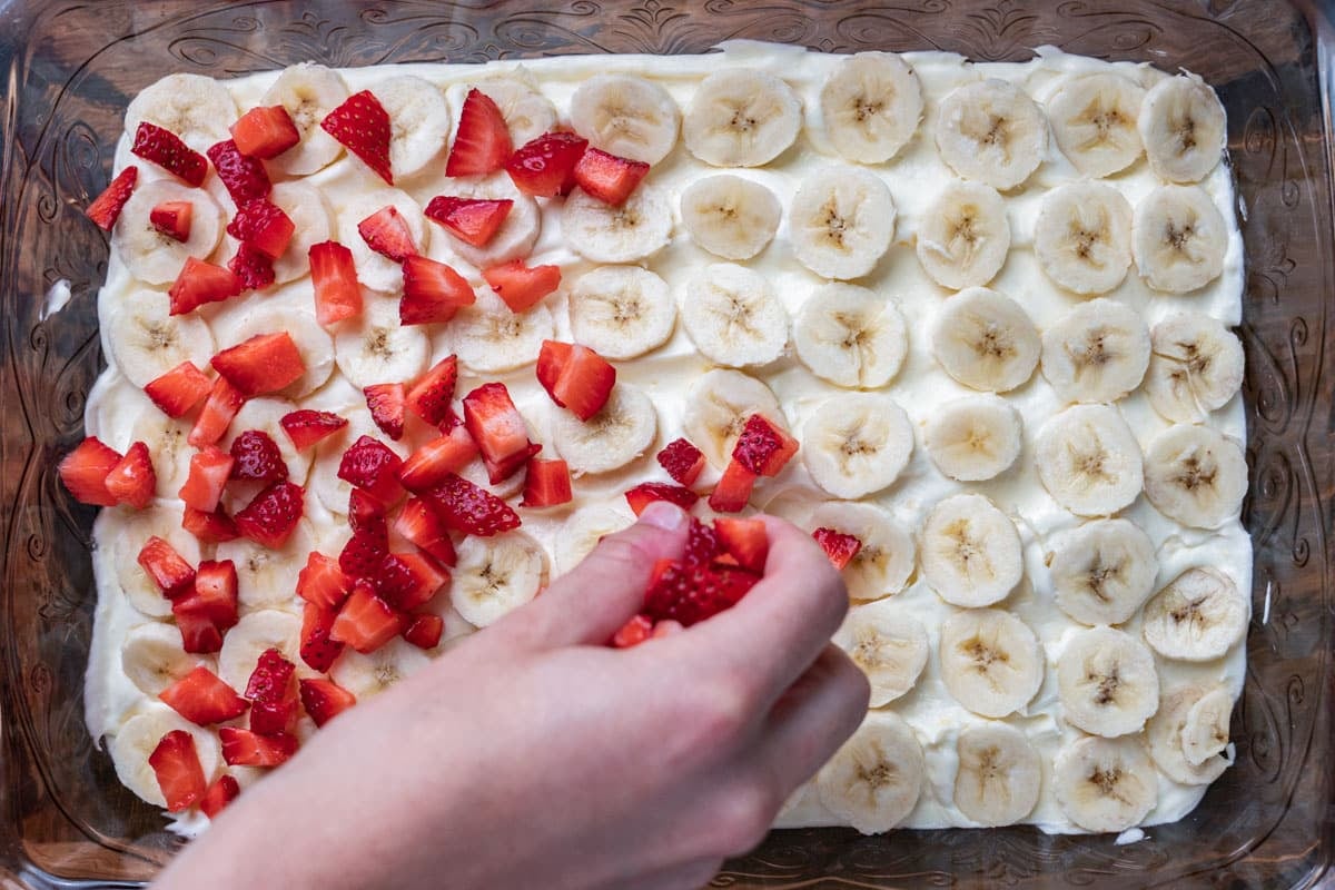 sprinkling strawberries over bananas in a pan