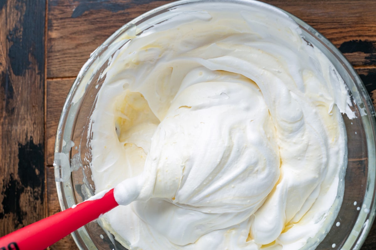 whipped cream in a bowl with a red spatula