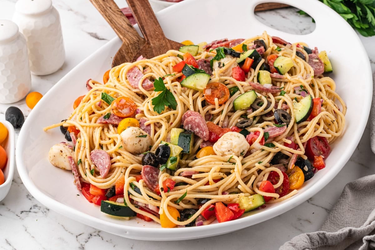 spaghetti salad in a white bowl with a spatula
